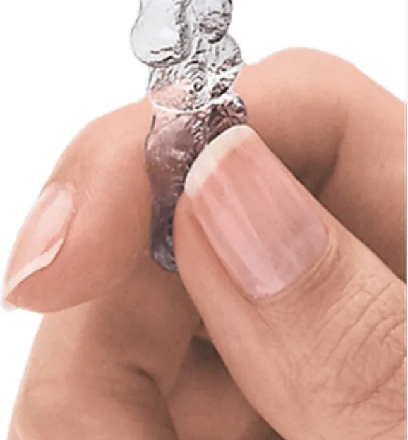 A clear Invisalign aligner held between two fingers